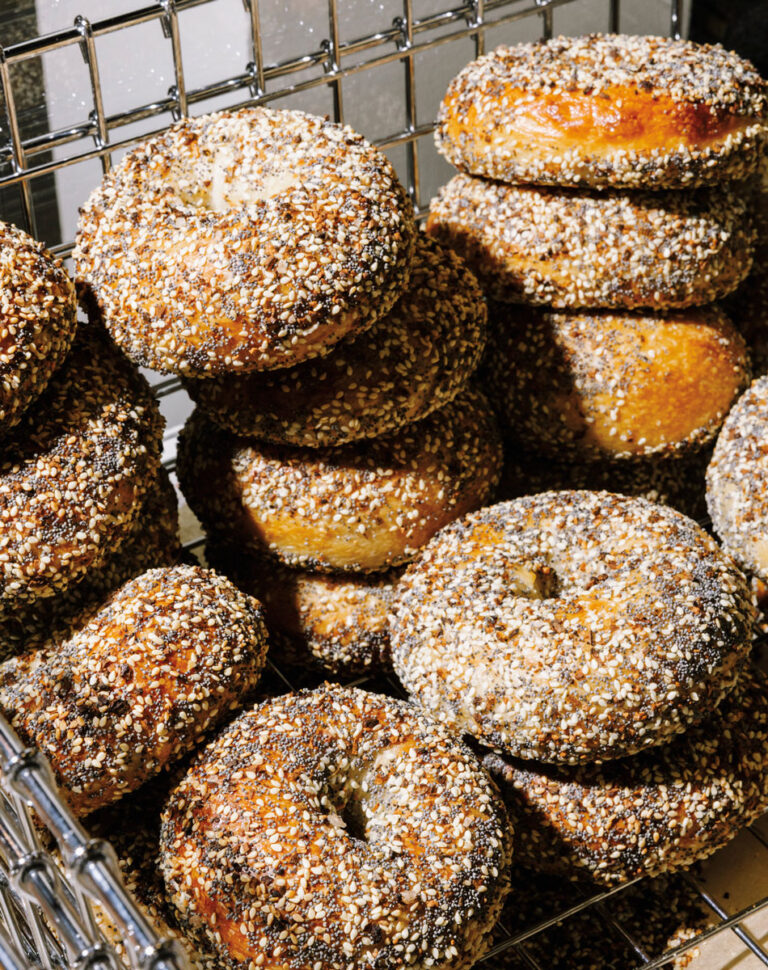 A metal basket filled with stacks of golden-brown everything bagels, topped with a mix of seeds, salt, and seasoning, ready to be enjoyed in the heart of the South Lake Union neighborhood.