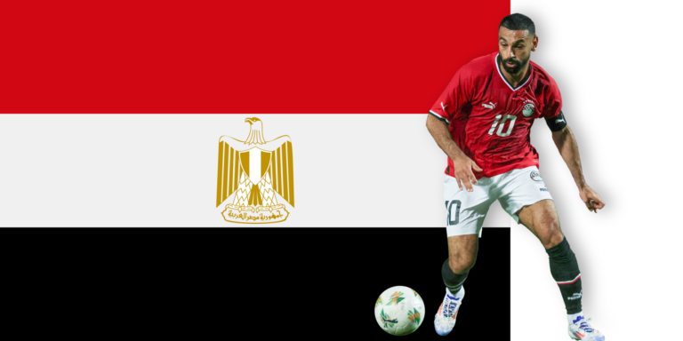 A soccer player in an Egypt jersey and black shorts stands ready beside a soccer ball, in front of the Egyptian flag featuring red, white, and black stripes with a gold eagle in the center.