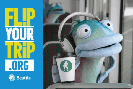 A blue puppet fish wearing headphones holds a coffee cup with a fish logo while sitting on a bus. Next to it, text reads 