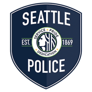 A navy blue Seattle Police badge featuring the words “Seattle Police,” “Est. 1869,” and a circular seal in the center with a profile of a woman and the words “Service Pride Dedication.”.