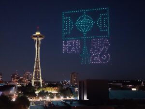 A night view of Seattle’s Space Needle with hundreds of illuminated drones forming a soccer field and “FIFA 26” in the sky, promoting the 2026 FIFA World Cup. City lights are visible below.