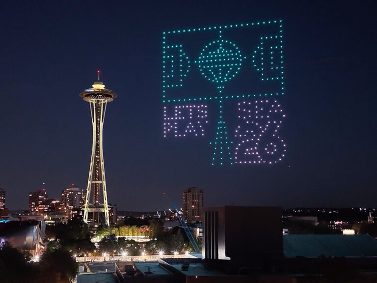 A night view of Seattle’s Space Needle with hundreds of illuminated drones forming a soccer field and “FIFA 26” in the sky, promoting the 2026 FIFA World Cup. City lights are visible below.