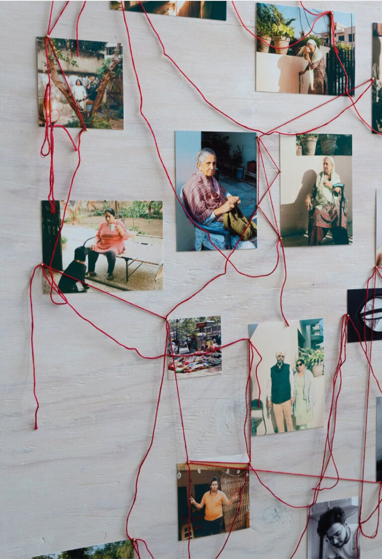 A collage of various photographs showing people in different settings, all connected by red string pinned to a light wooden board, creating a network or web-like pattern.