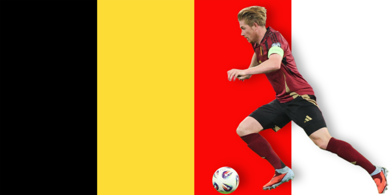 A soccer player in a red and black uniform is running with a ball in front of a background featuring the black, yellow, and red vertical stripes of the Belgian flag.