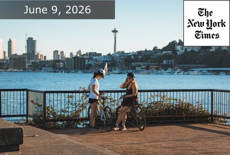 Two cyclists pause by a waterfront railing with the Seattle skyline and Space Needle in the background; "June 9, 2026" and "The New York Times" text appear at the top of the image.