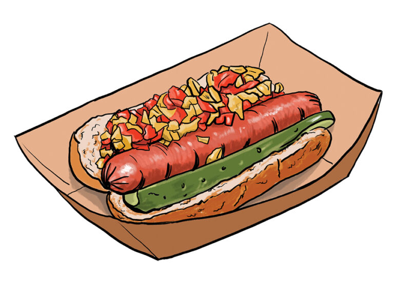 A hot dog in a paper tray topped with chopped onions, tomatoes, and relish, with a pickle spear placed alongside the sausage in a sliced bun.