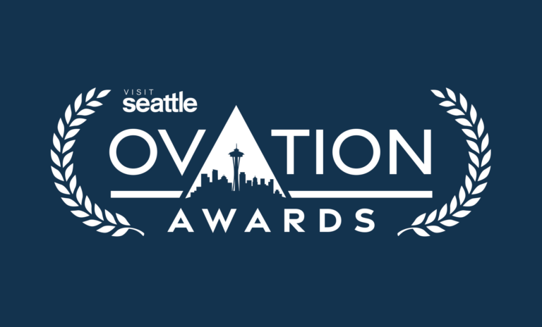 Logo for the Visit Seattle Ovation Awards, featuring laurel branches and the Seattle skyline inside the letter “A” in “Ovation” on a dark blue background.