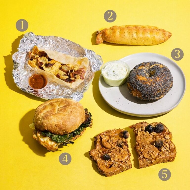 Five breakfast items numbered one through five: a breakfast burrito with salsa, a breadstick, a poppy seed bagel with cream cheese, a breakfast sandwich, and two slices of toast topped with nut butter, blueberries, and seeds on a yellow background.