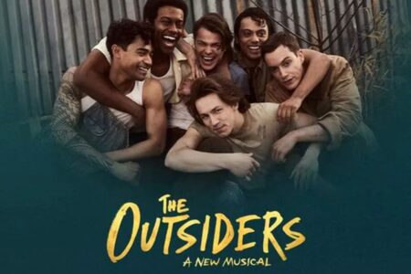 Six young men huddle together in a group photo for the musical “The Outsiders.”